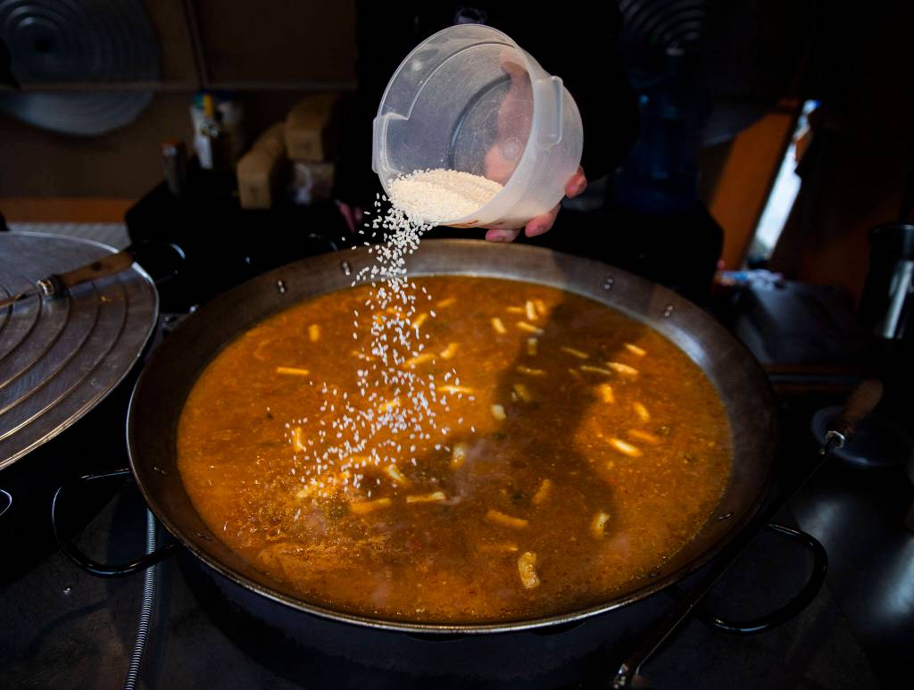 Rice is sprinkled into a large batch of paella at the Paella House food truck during the Snohomish Farmers Market on Thursday. (Olivia Vanni / The Herald)