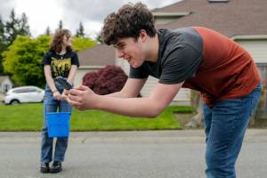 Sam Bowles records the run off the water from a chalk drawing with friend and co-artist, Rhyanna Mercer, Tuesday afternoon in Everett, Washington on May 10, 2022.  (Kevin Clark / The Herald)