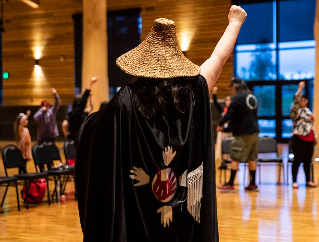 People raise their fists in support while listening to personal stories shared during a MMIW candlelight vigil at the Tulalip Gathering Hall on Thursday in Tulalip. (Olivia Vanni / The Herald)