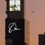 An airplane flies past the Boeing logo on the companys headquarters in Chicago in 2001. The company is expected to move its headquarters from Chicago to the Washington, D.C. area. (AP Photo/Ted S. Warren, File)