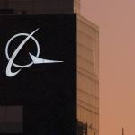 FILE - An airplane flies past the Boeing logo on the company's headquarters in Chicago, on Thursday, Dec. 20, 2001. Boeing Co., a leading defense contractor and one of the world's two dominant manufacturers of airline planes, is expected to move its headquarters from Chicago to the Washington, D.C., area, according to two people familiar with the matter. The decision could be announced as soon as later Thursday, May 5, 2022, according to one of the people. (AP Photo/Ted S. Warren, File)
