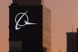 FILE - An airplane flies past the Boeing logo on the company's headquarters in Chicago, on Thursday, Dec. 20, 2001. Boeing Co., a leading defense contractor and one of the world's two dominant manufacturers of airline planes, is expected to move its headquarters from Chicago to the Washington, D.C., area, according to two people familiar with the matter. The decision could be announced as soon as later Thursday, May 5, 2022, according to one of the people. (AP Photo/Ted S. Warren, File)