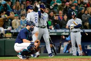 Tampa Bay Rays' Brandon Lowe (8) celebrates with Manuel Margot at home plate after hitting a home run, next to Seattle Mariners catcher Cal Raleigh during the sixth inning of a baseball game Saturday, May 7, 2022, in Seattle. (AP Photo/Jason Redmond)
