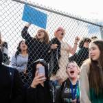 North Middle School eighth graders Cynthia Espinoza (left) and Fern Conroy (right) chant with Everett High School students from the other side of a perimeter fence surrounding the middle school on Monday. (Olivia Vanni / The Herald)