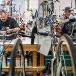 Juan Luna (left) and Jeff Austin tune up bicycles Tuesday at Sharing Wheels Community Bike Shop to be donated to child refugees from Afghanistan and Ukraine. (Kevin Clark / The Herald)