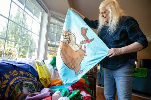 Melissa Batson unfurls a Groundhog Day flag designed by her niece Wednesday, May 11, 2022, at her home in Monroe, Washington. (Ryan Berry / The Herald)