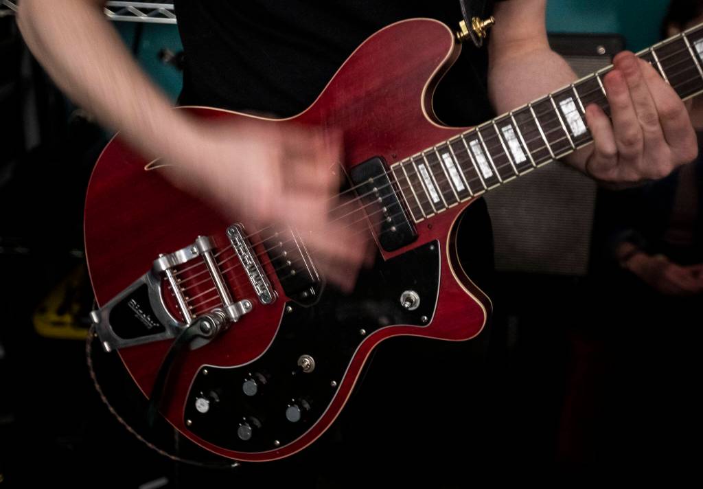 Christian Smith plays guitar while the band practices on May 17 in Everett. (Olivia Vanni / The Herald)