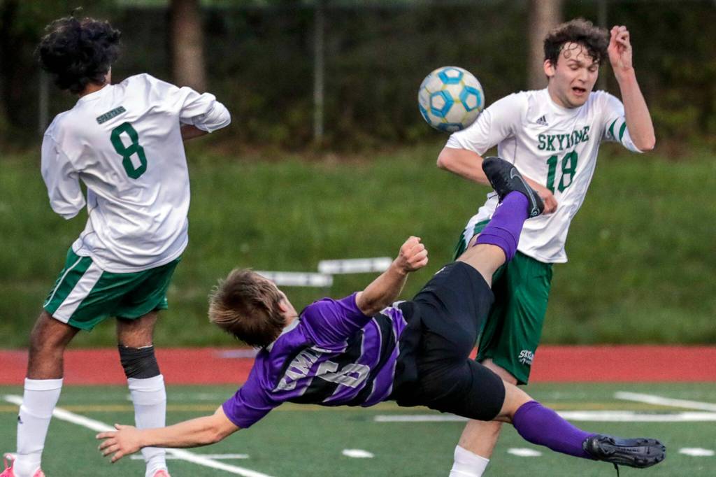 Kamiaks Christian Rivillas bicycle kicks with Skylines Vishnu Varadhan, left, and Charles Gall defending during a winner-to-state bi-district semfinal game Tuesday evening at Kamiak High School in Mukilteo. (Kevin Clark / The Herald)