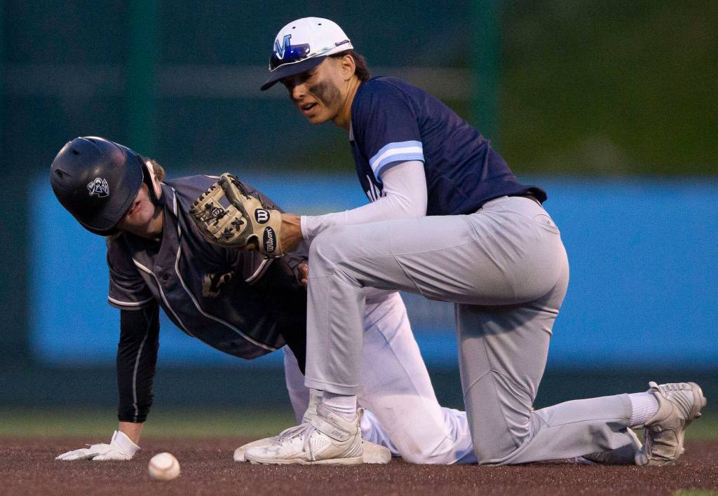 Lynnwoods Mason Lane (left) gets up after sliding into second base while Meadowdales Zaid Flynn looks for the ball he dropped during the district semifinal game at Funko Field on Tuesday in Everett. (Olivia Vanni / The Herald)