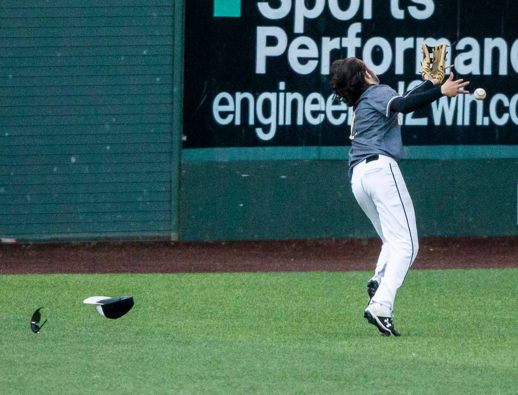 Lynnwoods Collin Morgan loses his hat and sunglasses while running to catch a fly ball during the district semifinal game at Funko Field on Tuesday in Everett. (Olivia Vanni / The Herald)