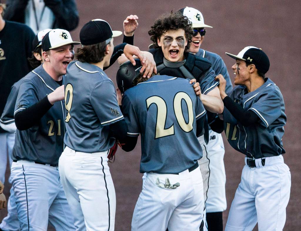 Lynnwood senior Mason Lane is congratulated by his teammates after scoring in the first inning. (Olivia Vanni / The Herald)