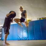 Miranda Granger jumps in the air to knee a medicine ball being held by Charlie Pearson during her training session at Charlies Combat Club on Friday, July 26, 2019, in Everett. (Olivia Vanni / The Herald)