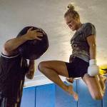 Miranda Granger jumps in the air to knee a medicine ball being held by Charlie Pearson during her training session at Charlie's Combat Club on Friday, July 26, 2019 in Everett, Wash. (Olivia Vanni / The Herald)