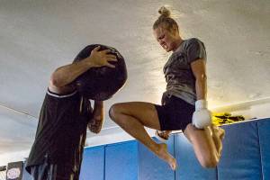 Miranda Granger jumps in the air to knee a medicine ball being held by Charlie Pearson during her training session at Charlie's Combat Club on Friday, July 26, 2019 in Everett, Wash. (Olivia Vanni / The Herald)