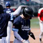 Meadowdales Nicholas Banez pats the helmet of teammate Nicholas Blas after Blas scored a 7th-inning run against Stanwood Saturday, May 14, 2022, during a 3A district matchup at Funko Field in Everett, Washington. (Ryan Berry / The Herald)