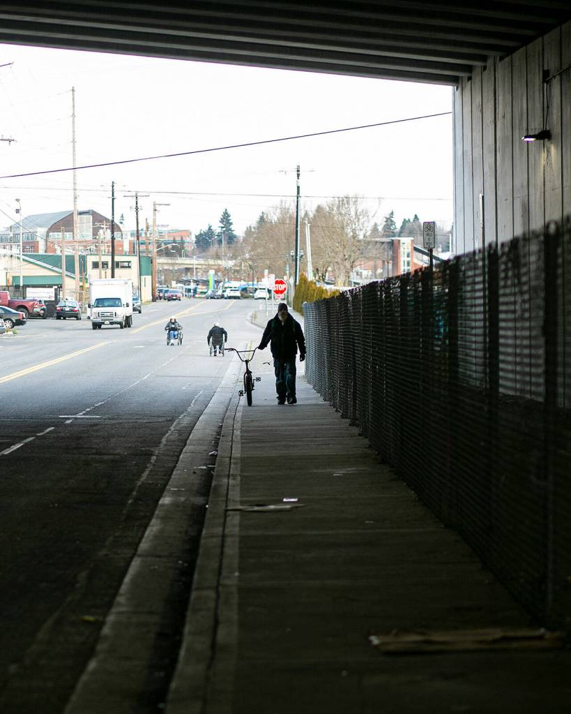 A man walks his bike through an underpass next to the Everett Gospel Mission Feb. 22 in Everett. According to point-in-time count volunteers, the area in years past was a common place to find people experiencing homelessness. (Ryan Berry / The Herald)