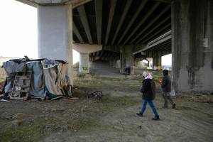 Mandy Jeffcott and Aaron King explore the area beneath a highway underpass while conducting a PIT count Tuesday, Feb. 22, 2022, in Everett, Washington. (Ryan Berry / The Herald)