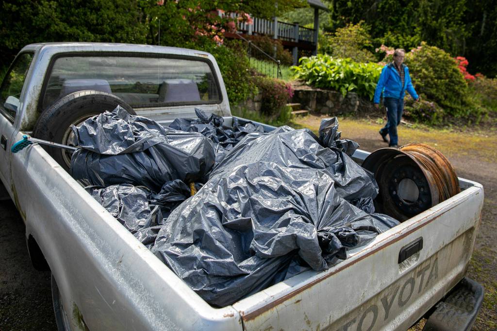 Doug Ewing heads out to his pickup truck, which currently holds his 59th load of trash cleaned up from a small stretch of the Snohomish River. (Ryan Berry / The Herald)