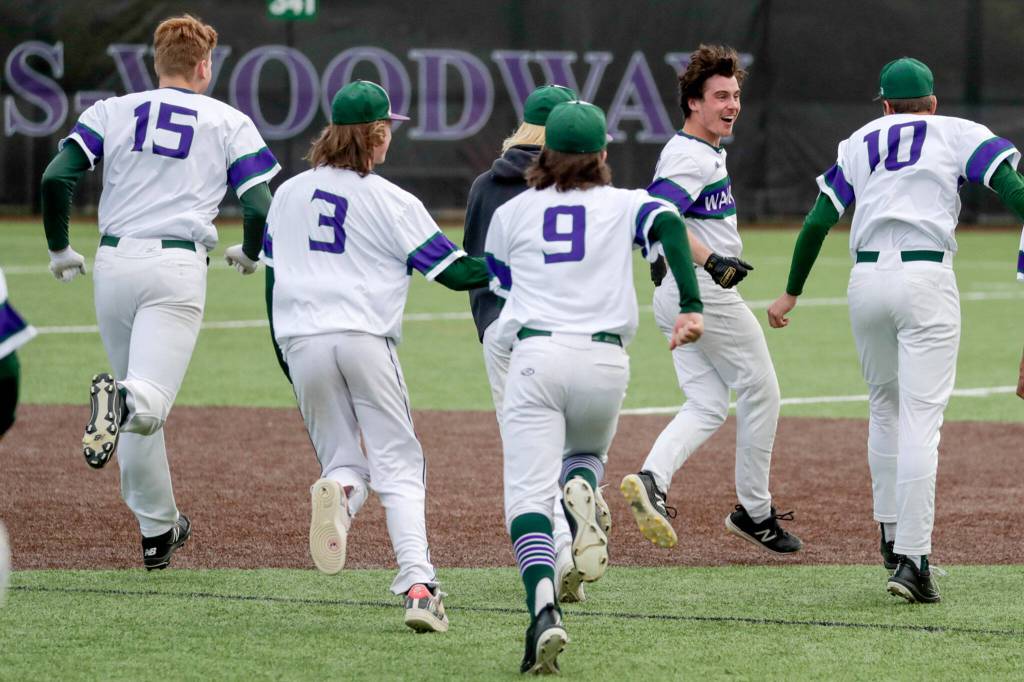 Edmonds-Woodway players rush toward teammate Jack Beers (facing) after he drove in the game-winning run. (Kevin Clark / The Herald)
