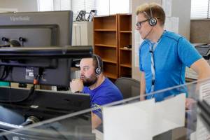 Wade Brickman works through a call with trainer Lars Coleman Friday afternoon at SNO911 in Everett, Washington on May 20, 2022. (Kevin Clark / The Herald)