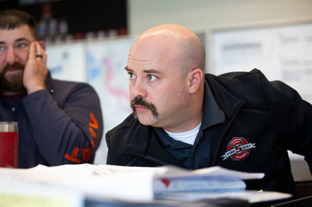 New Sultan Fire Chief Seth Johnson leans in to listen to fellow emergency workers during a disaster simulation Wednesday at Snohomish County Fire District 5 Station 51 in Sultan. (Ryan Berry / The Herald)