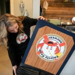 Erin Hanson shows off one of the custom bean bag toss boards available to customers at Thirsty Crab Brewery in Clinton. (Ryan Berry / The Herald)