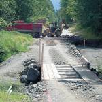 An excavator loads pieces of old roadway into a dump truck at the site of a washout on Olympic Hot Springs Road in the Elwha Valley of Olympic National Park in 2016. (Keith Thorpe / Peninsula Daily News file)