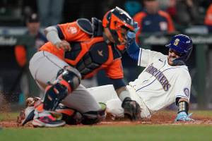 Seattle Mariners' Luis Torrens, right, slides safely home past Houston Astros catcher Martin Maldonado to score on a RBI single hit by Ty France during the sixth inning of a baseball game, Sunday, May 29, 2022, in Seattle. (AP Photo/Ted S. Warren)