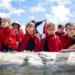 Young girls watch as a canoe carrying an enormous king salmon makes its way to shore on June 11 in Tulalip. (Olivia Vanni / The Herald)