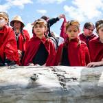 Young girls watch as a canoe carrying an enormous king salmon makes its way to shore on Saturday, June 11, 2022, in Tulalip, Washington. (Olivia Vanni / The Herald)
