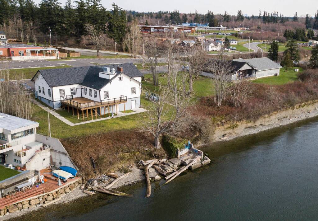 Below the former Tulalip Indian School dining hall, remnants of the federal jail are visible along the water at Tulalip Bay. (Olivia Vanni / The Herald)