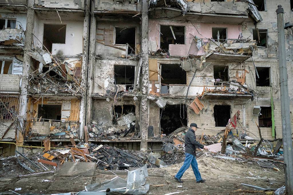 A man walks past a building damaged following a rocket attack in Kyiv on Feb. 25. (AP Photo/Emilio Morenatti, File)