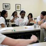 Teenagers listen to 15-year-old Glodie Wabaluku (center) read a poem she wrote during Leadership Launchs Emotion Commotion event. (Ryan Berry / The Herald)