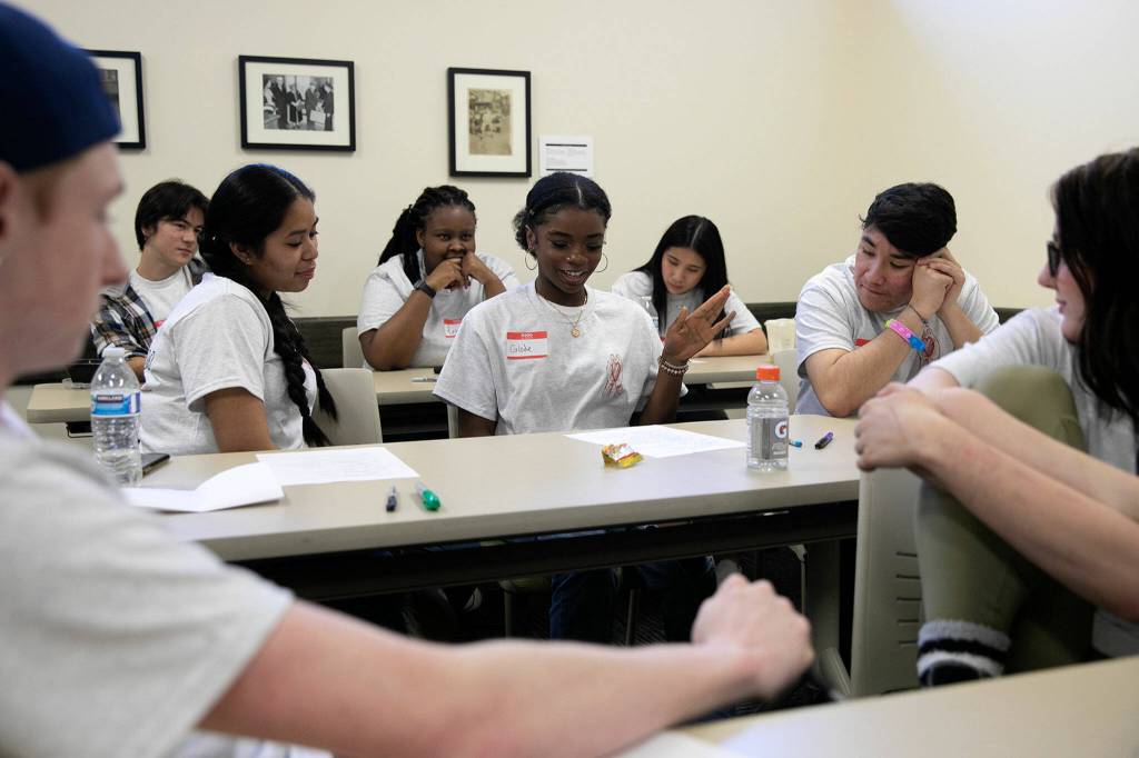 Teenagers listen to 15-year-old Glodie Wabaluku (center) read a poem she wrote during Leadership Launchs Emotion Commotion event. (Ryan Berry / The Herald)