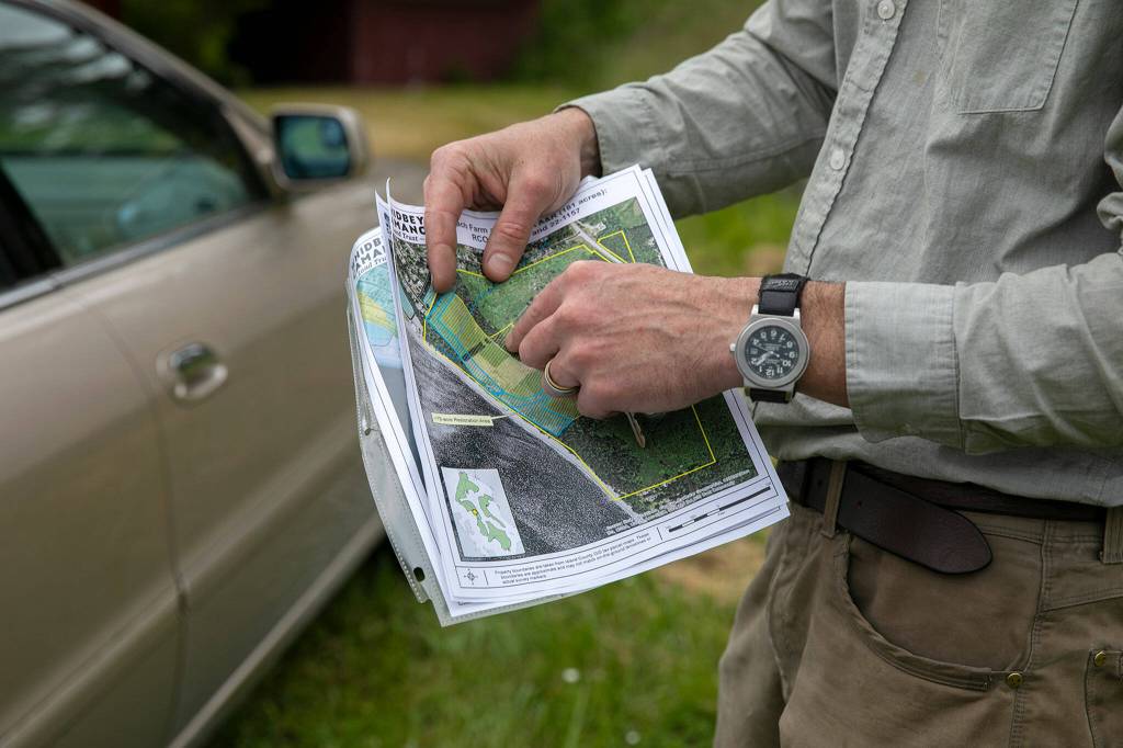 Ryan Elting, conservation director at the Whidbey Camano Land Trust, points out the boundaries of the Keystone Preserve while touring the area on June 10. near Coupeville. (Ryan Berry / The Herald)