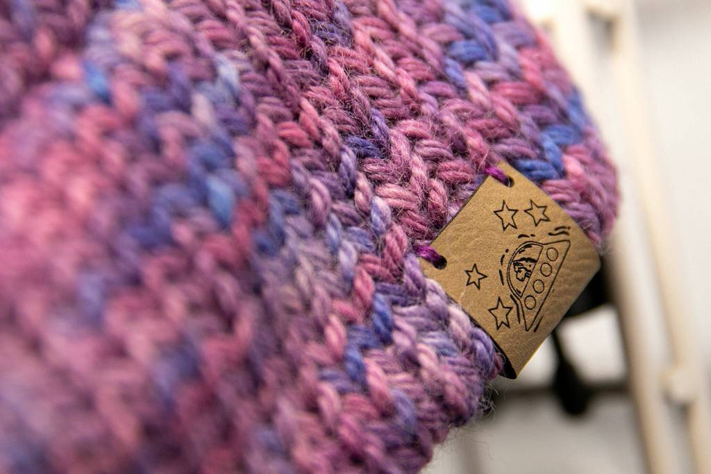 A tag featuring an alpaca in a flying saucer adorns an alpaca fleece hat inside the farms gift shop Monday, March 28, 2022, at Alpacas from MaRS in Snohomish, Washington. (Ryan Berry / The Herald)