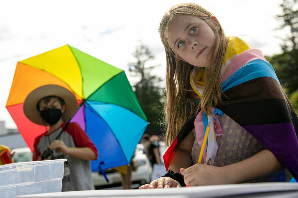 Third-grader Myly Smock draws a sign to hold up during a rally in support of LGBTQ+ students on Monday in front of the Marysville School District Service Center in Marysville. (Ryan Berry / The Herald)