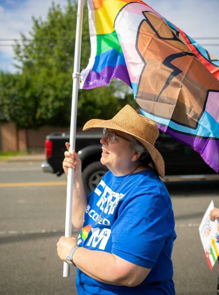 Cynthia Tamlyn waves a flag as cars drive past during a rally in support of LGBTQ+ students on Monday in front of the Marysville School District Service Center in Marysville. (Ryan Berry / The Herald)