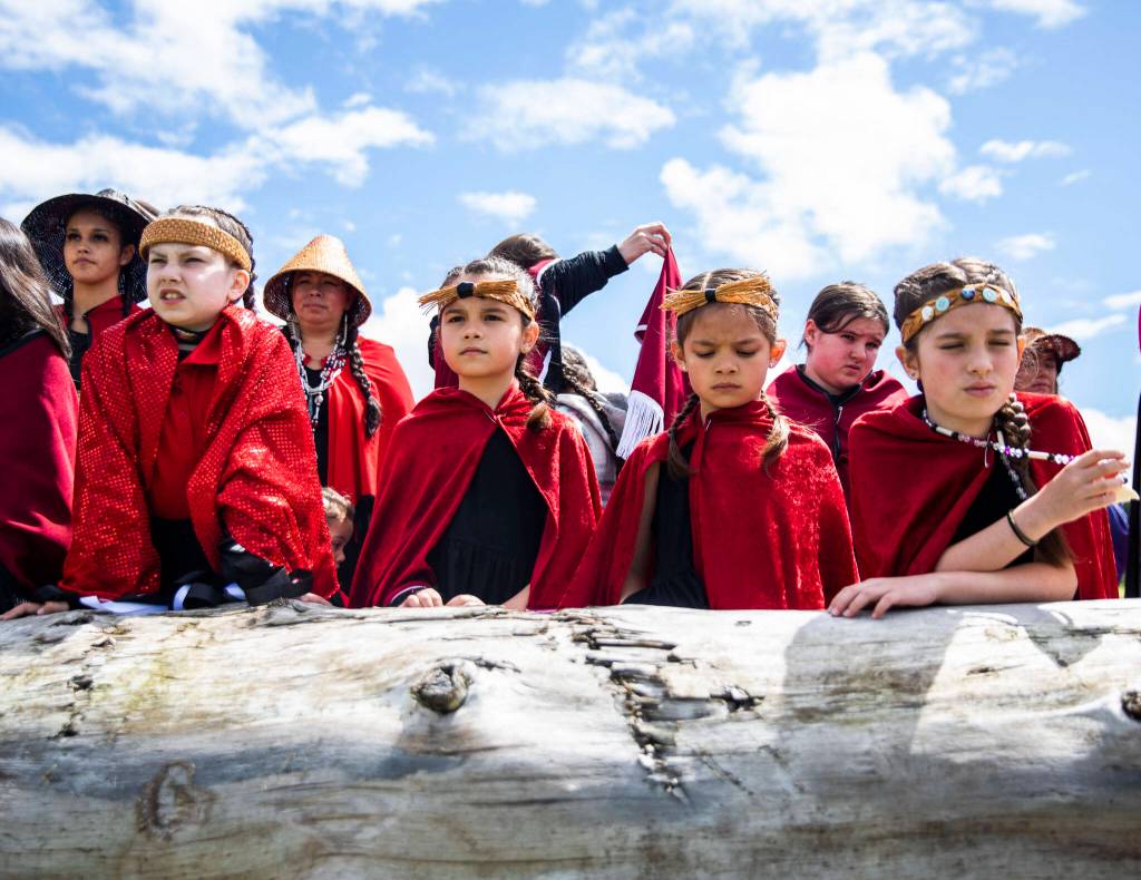 Young girls watch as a canoe carrying a salmon makes its way to shore on Saturday in Tulalip. (Olivia Vanni / The Herald)