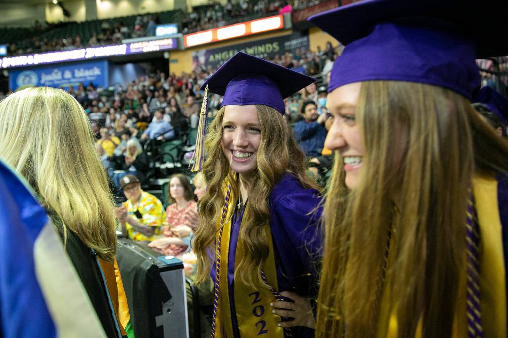The first two students in line laugh nervously as they await Pomp and Circumstance during Lake Stevens High Schools 2022 commencement ceremony Tuesday at Angel of the Winds Arena in Everett. (Ryan Berry / The Herald)