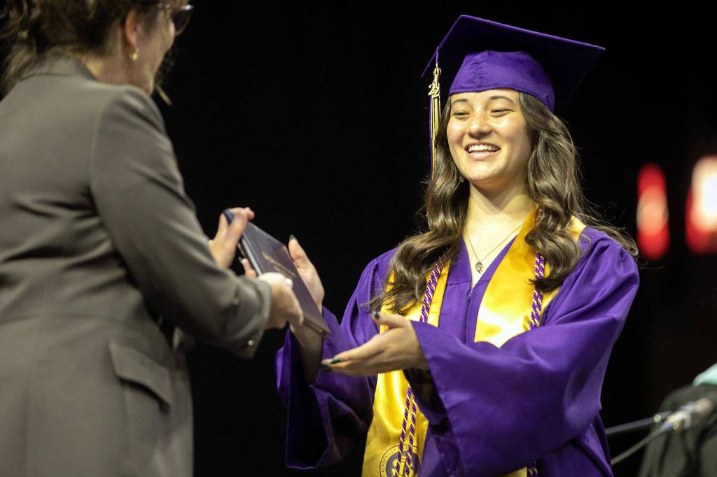A student receives her diploma during Lake Stevens High Schools 2022 commencement ceremony Tuesday at Angel of the Winds Arena in Everett. (Ryan Berry / The Herald)