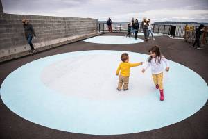 Siblings Penelope White, 4, and Edward White, 1, play tag on one of the large painted circles in the Parklet along the Mukilteo waterfront on Sunday, June 12, 2022. (Olivia Vanni / The Herald)