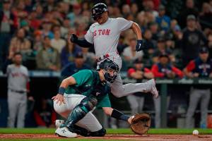 Boston Red Sox's Rafael Devers, top, scores on an RBI-double hit by Xander Bogaerts as Seattle Mariners catcher Cal Raleigh, bottom, reaches for the ball during the first inning of a baseball game, Friday, June 10, 2022, in Seattle. (AP Photo/Ted S. Warren)
