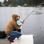 Ridley Biggs (right), 5, learns how to cast with her father, Mike Biggs, as it starts to rain on Friday in Lake Stevens. (Olivia Vanni / The Herald)