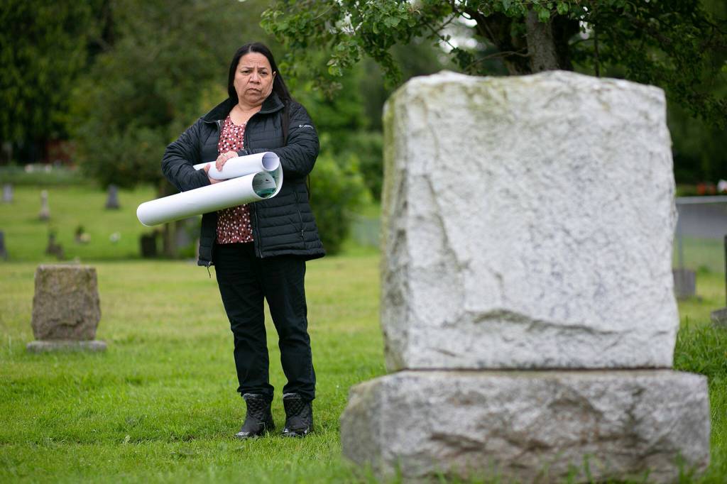 Candy Hill-Wells takes a moment to read a grave marker June 14 at Mission Beach Cemetery in Tulalip. (Ryan Berry / The Herald)