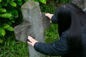 Candy Hill-Wells, funeral services officer for the Tulalip Tribes, tries to read the weathered letters on a grave marker Tuesday, June 14, 2022, at Priest Point Cemetery in Tulalip, Washington. (Ryan Berry / The Herald)