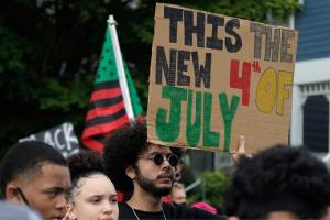 A person taking part in a Juneteenth march in Seattle holds a sign that reads "This the new 4th of July," Friday, June 19, 2020. Thousands of people marched to honor the Juneteenth holiday and to protest against police violence and racism. Juneteenth marks the day in 1865 when federal troops arrived in Galveston, Texas, to take control of the state and ensure all enslaved people be freed, more than two years after the Emancipation Proclamation. (AP Photo/Ted S. Warren)