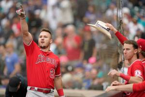 Los Angeles Angels' Mike Trout, left, points toward the outfield as he is greeted at the dugout after hitting a two-run home run in the tenth inning of the first baseball game of a doubleheader against the Seattle Mariners, Saturday, June 18, 2022, in Seattle. The Angels won 4-2 in ten innings. (AP Photo/Ted S. Warren)