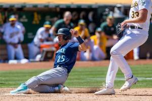 Seattle Mariners' Dylan Moore (25) scores on a wild pitch by Oakland Athletics' A.J. Puk (33) during the ninth inning of a baseball game in Oakland, Calif., Thursday, June 23, 2022. (AP Photo/John Hefti)