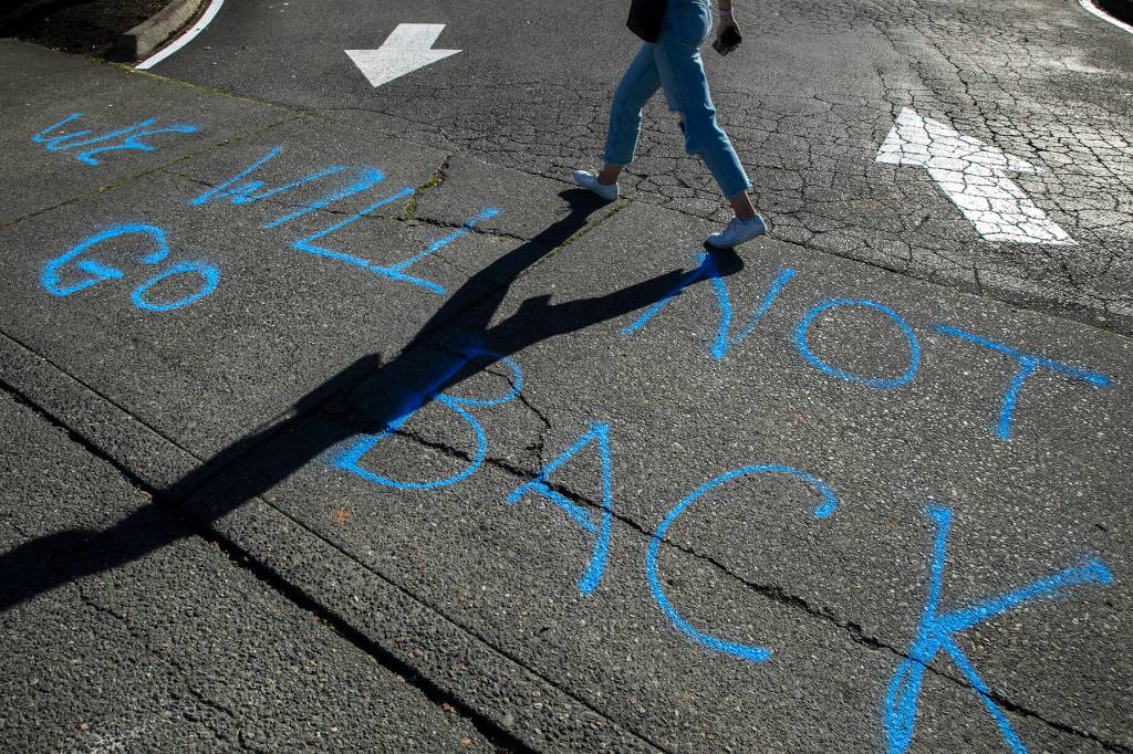 A woman walks past writing saying, We will not go back, during a protest against the Supreme Courts decision to overturn Roe v. Wade on Friday along Broadway in Everett, Washington. (Ryan Berry / The Herald)